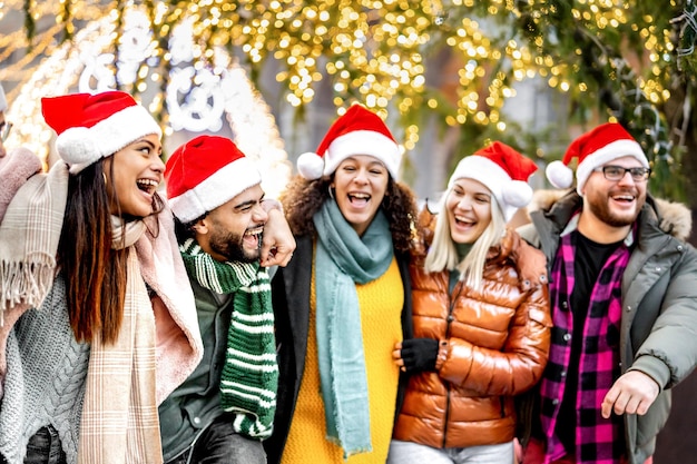 Gruppo di giovani amici che camminano sotto le decorazioni dell'albero di natale