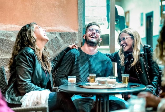 Young friends having genuine fun drinking on happy hour at street bar