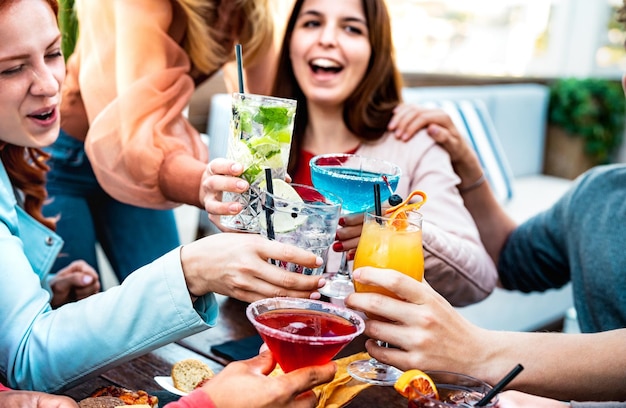 Photo young friends holding multicolored drinks