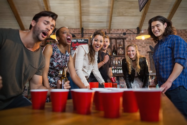 Young friends playing beer pong game in bar