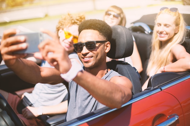 Photo young friends take a selfie in a cabriolet car