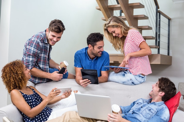 Young friends using modern technologies on sofa 