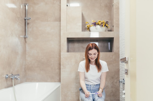 Young frustrated woman looking at a quick positive or negative result pregnancy test