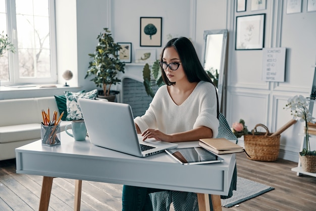 Young and full of ideas. Beautiful young woman working using laptop while sitting in home office