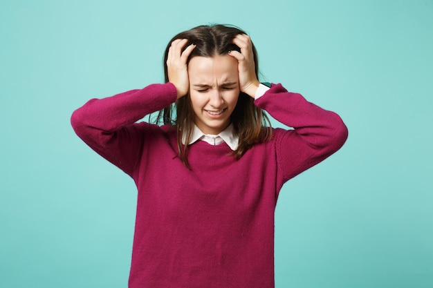 Young fun sad upset perplexed disturb brunette woman girl put hands on head posing isolated on blue wall background studio portrait. People sincere emotions lifestyle concept. Mock up copy space.