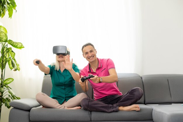 Giovane coppia divertente che gioca ai videogiochi occhiali per realtà virtuale nel loro appartamento - persone felici che si divertono con le nuove tendenze tecnologiche - concetto di gioco - focus on woman joypad