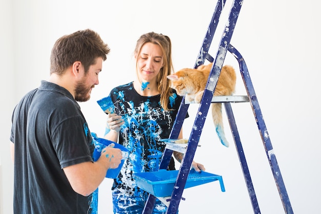 Giovane coppia divertente con il gatto facendo lavori di ristrutturazione nel nuovo appartamento.
