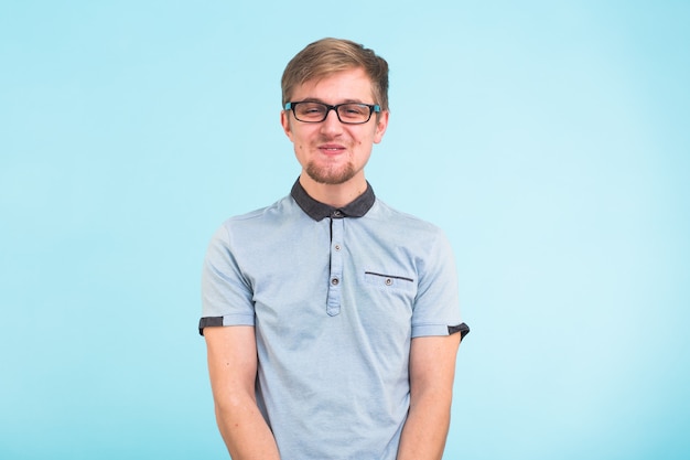 Young funny man wears spectacles isolated over blue