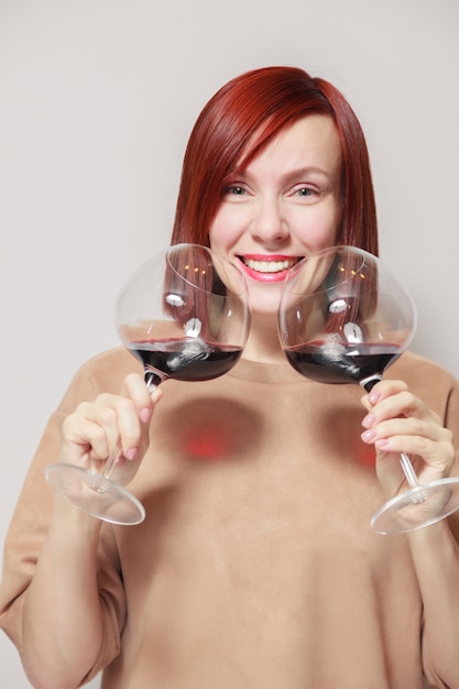 Young funny redhaired woman sommelier with wine glasses