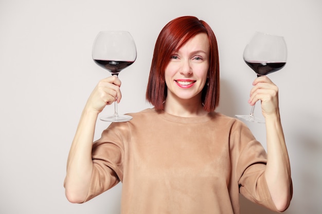 Young funny redhaired woman sommelier with wine glasses