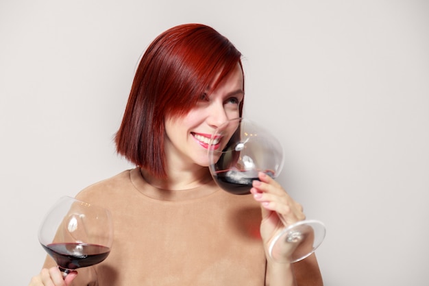 Young funny redhaired woman sommelier with wine glasses