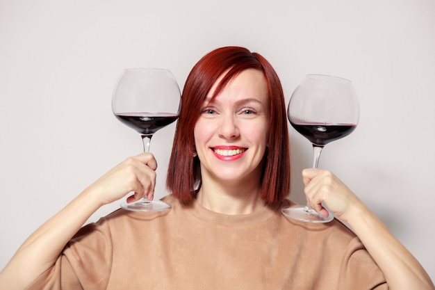 Giovane sommelier dai capelli rossi divertente della donna con i vetri di vino