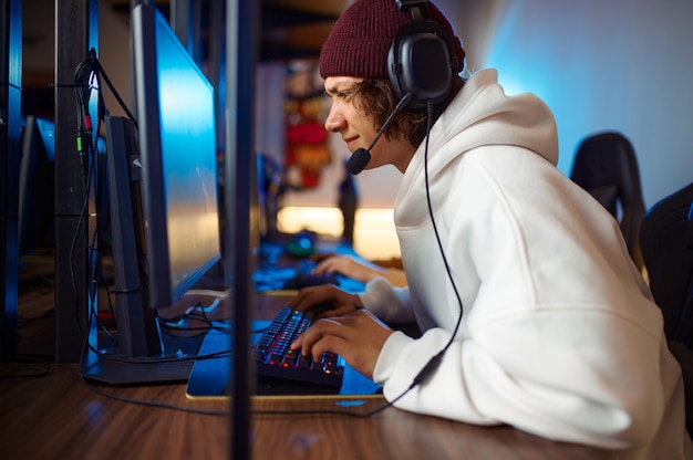 Young gamer in headset play shooter in game club