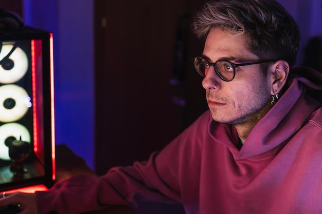 Young gamer with glasses and pink sweater playing video games all night