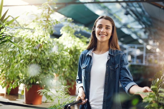 Young gardener collecting plants for sale in her own greenhouse online store