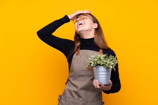 Молодая девушка садовник держит растение смеется