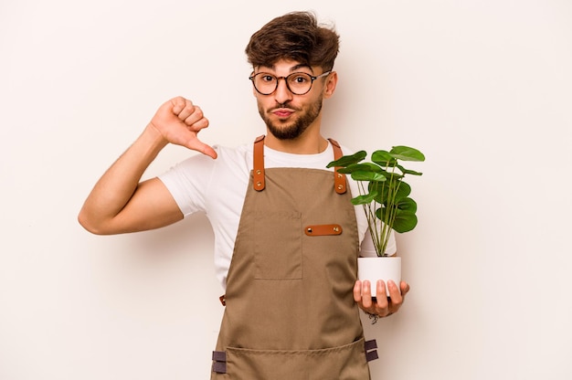 Молодой садовник латиноамериканец, держащий растение на белом фоне, чувствует себя гордым и самоуверенным примером для подражания
