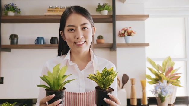 Young gardener woman holding flowerpot in the room.