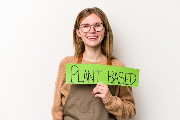 Young gardener woman holding a plan based placard isolated on white background happy smiling and cheerful