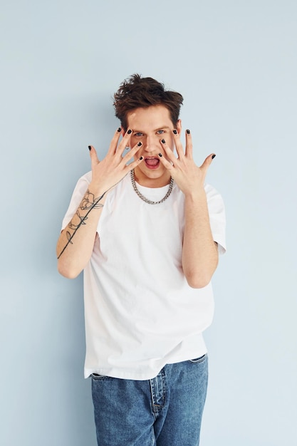 Young gay man is standing in the studio and posing for a camera Red colored lips