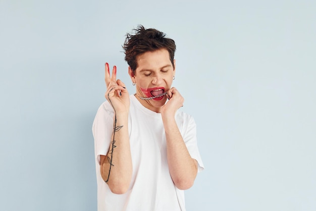 Young gay man is standing in the studio and posing for a camera Shows gestures