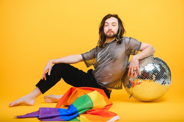 Young gay man is standing in the studio and posing for a camera