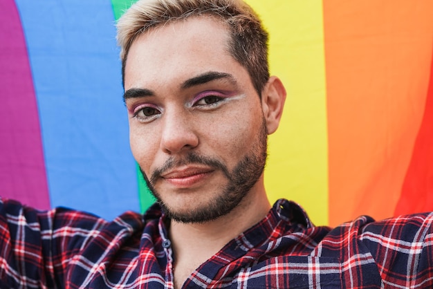 LGBT Rainbwo 깃발을 들고 카메라를 보고 있는 젊은 게이 남자