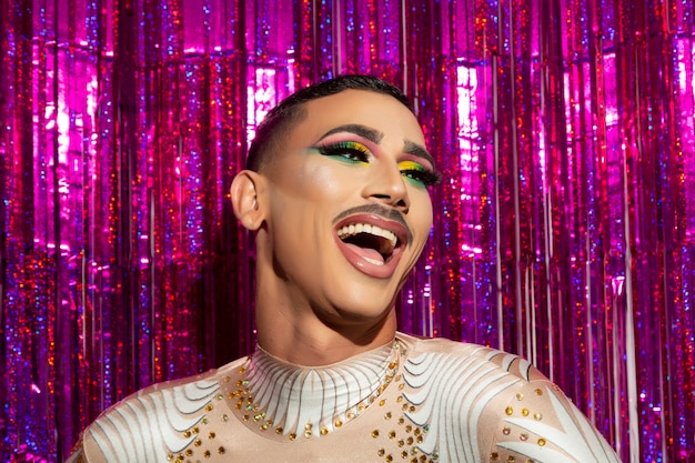 Young gay man with makeup happy smiling with a colorful background