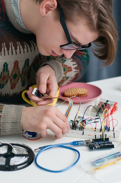 Young geek connecting wires to breadboard.