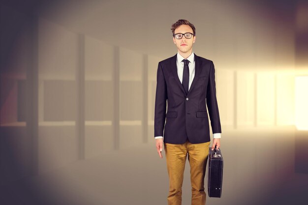 Young geeky businessman holding briefcase against bright light in a curved room