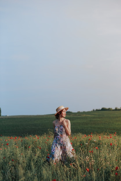 夕日の光線でリラックスした穏やかな若い女性。花畑の完全な長さの肖像画