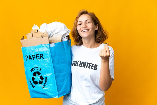 Young Georgian woman holding a recycling bag full of paper to recycle making money gesture