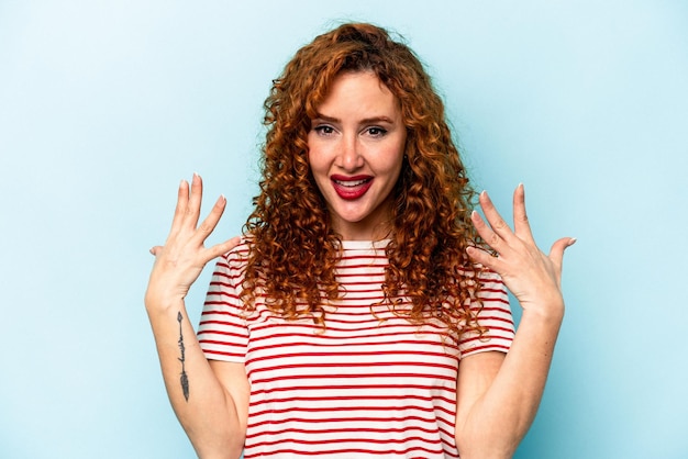 Young ginger caucasian woman isolated on blue background showing number ten with hands