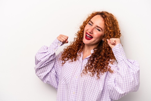 Young ginger caucasian woman isolated on white background raising fist after a victory winner concept