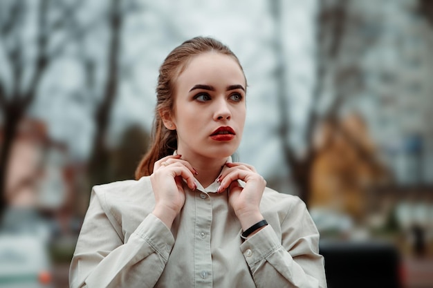 Young ginger redhead business woman hold straightens white shirt collar