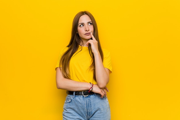 Young ginger redhead woman looking sideways with doubtful and skeptical expression