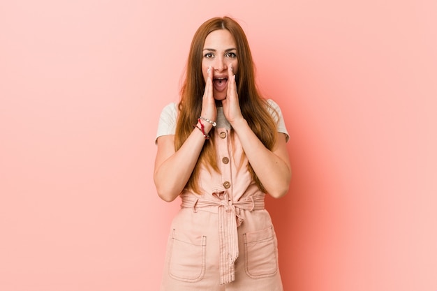 Young ginger woman with freckles shouting excited to front.