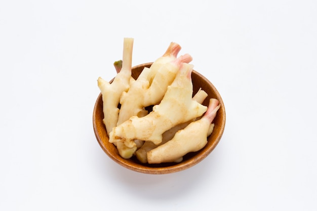 Young ginger in wooden bowl on white background.