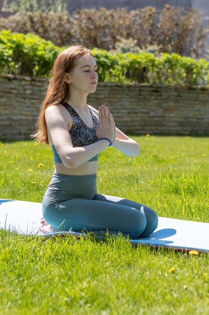 A young girl adheres to a healthy lifestyle and does yoga outdoors