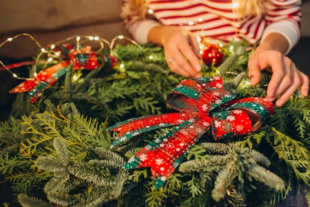 若い女の子は、モミと松の小枝のクリスマスリース、花輪を飾ります、