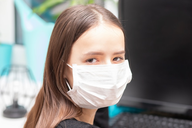 Giovane ragazza in maschera antibatterica al lavoro in ufficio