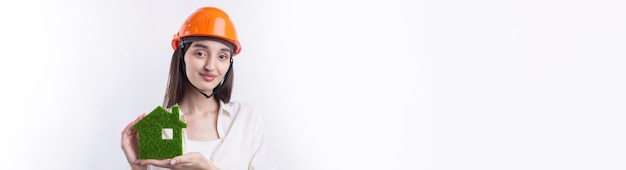 건설 헬멧을 쓴 어린 소녀 건축가가 친환경 부동산 판매 모델을 보여줍니다.