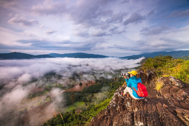 若い女の子は、高山の霧の海の写真を撮っています。