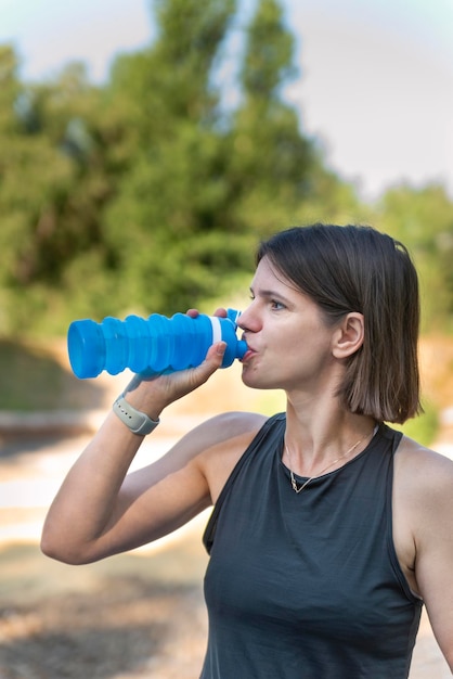 Young girl athlete drinks water from silicone bottle during training Portrait of sportive woman workout