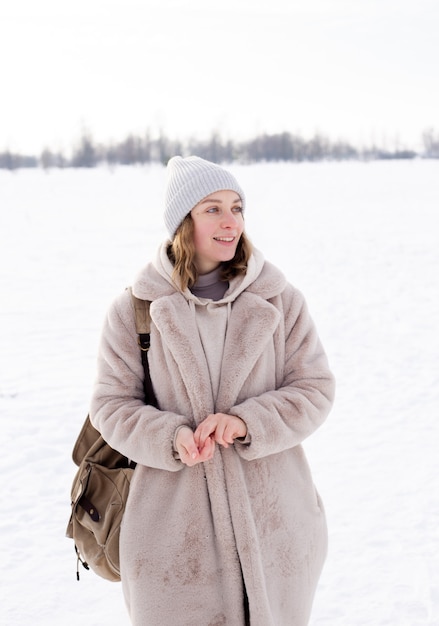 Young girl in beige clothes fur coat made of artificial fur walks in winter