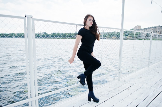 Young girl at black clothes posed on the pier