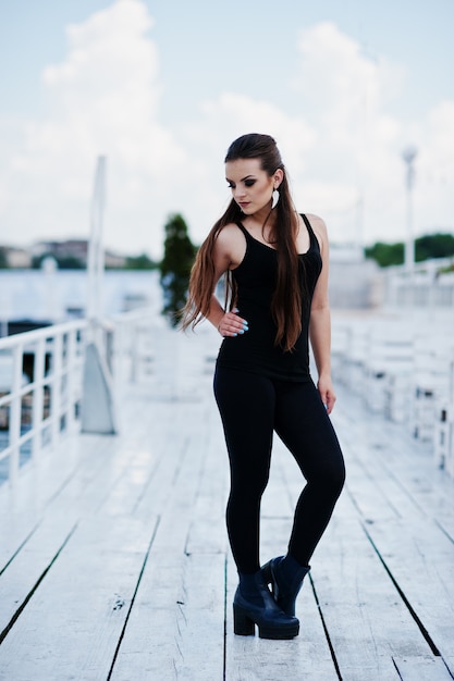 Young girl at black clothes posed on the pier