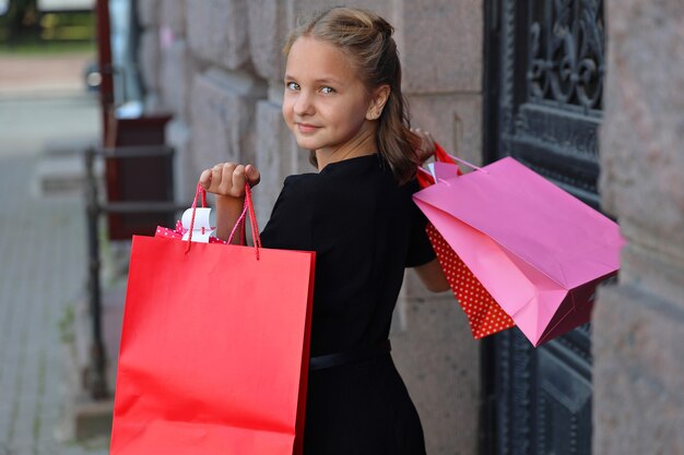 Young girl in a black dress with colored bags