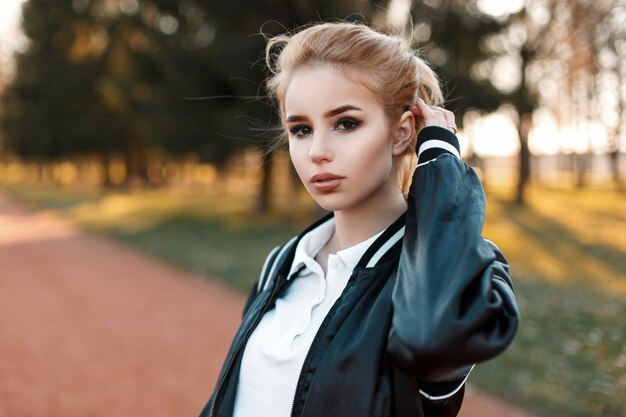 Young girl in a black jacket and white polo in the park on a sunny day