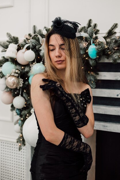 Young girl in a black long dress posing in the New Years hall with gloves